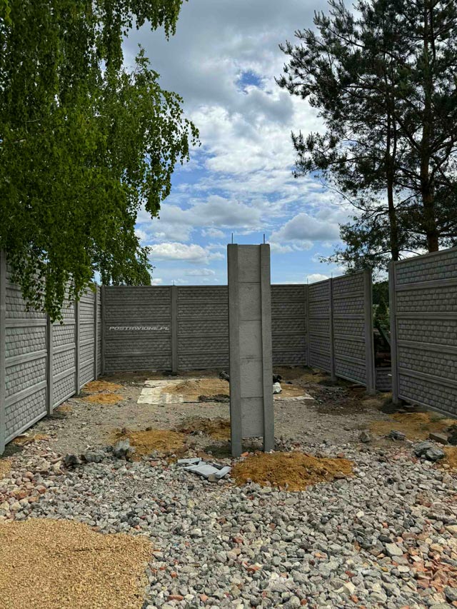 Budowa wiaty z prefabrykowanych płyt betonowych na tle zieleni i nieba.